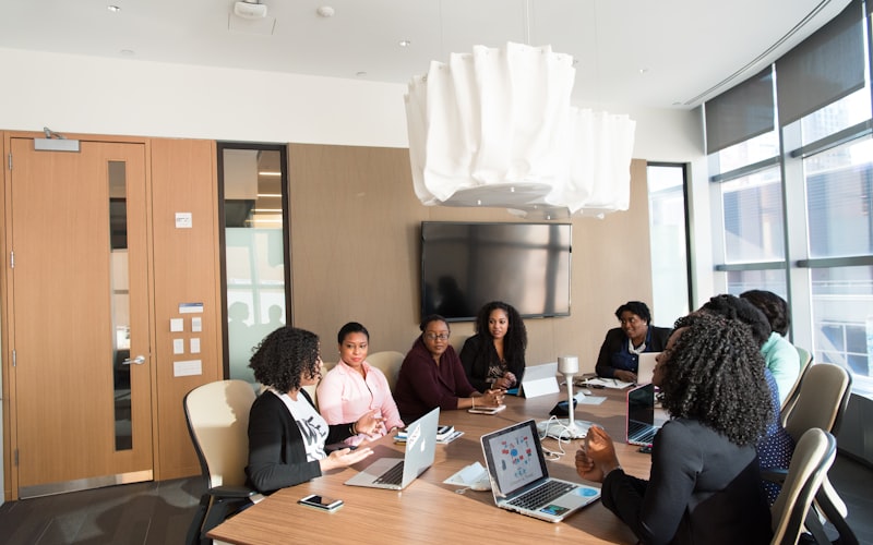 A team seated around a boardroom table with laptops during a meeting